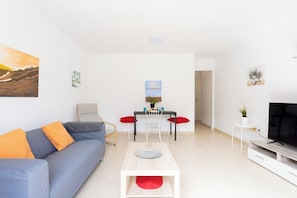 Un salon moderne comprenant un canapé, une table à manger, des chaises et un téléviseur.