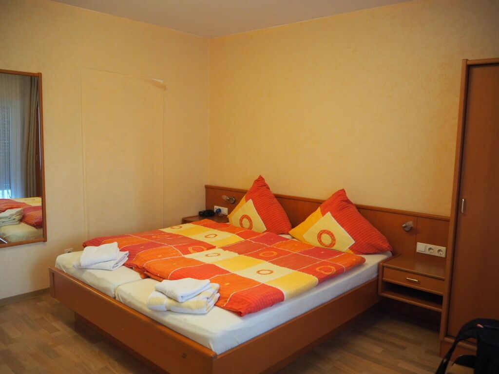 Een eenpersoonsbed met houten frame, een nachtkastje en een kledingkast.