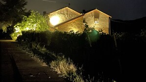 A house with a sloped roof, a visible chimney, and a lit window. - Weingut & Gästehaus Andreas Erz (Brauneberg)