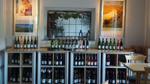 A wine bar with shelves of wine bottles and framed posters on the walls. - Weingut & Gästehaus Andreas Erz (Brauneberg)
