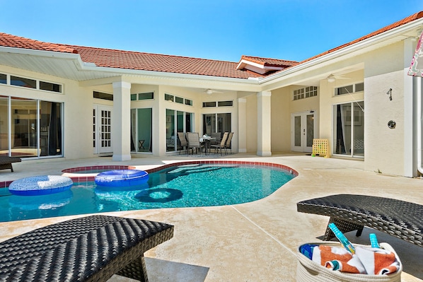 A swimming pool with lounge chairs and a covered patio area.