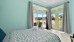 A hotel room with a bed, a view of a swimming pool, and a balcony. - Luxury Courtyard Home w/ Heated Pool/Spa & In-law Suite, 2 Min Walk to Beach! (New Smyrna Beach)