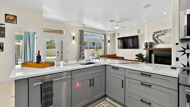 A modern kitchen with grey cabinets, a white countertop, and a built-in oven. - Luxury Courtyard Home w/ Heated Pool/Spa & In-law Suite, 2 Min Walk to Beach! (New Smyrna Beach)