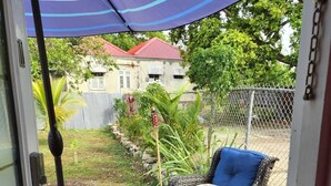Un patio con muebles de mimbre, una mesa y un paraguas azul.