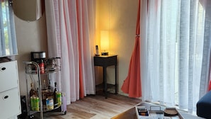 Habitación de hotel con piso de madera, un escritorio con lámpara, un minibar y una zona de estar con una bandeja de objetos.
