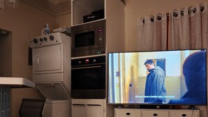 Cocina compacta con microondas, horno y televisor empotrado.