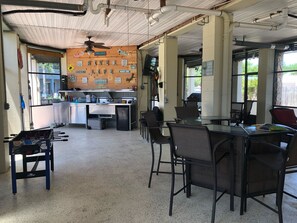 Ett rum med ett litet kök, ett fotbollsspel och en sittgrupp med stolar och ett bord.