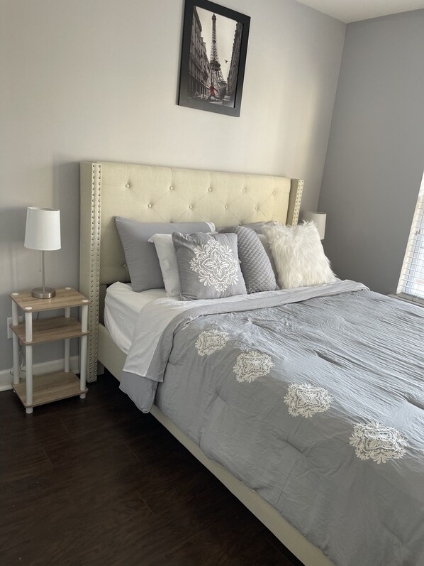 A bedroom with a bed, bedside tables, and a framed picture of the Eiffel Tower.