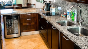 A modern kitchen with granite countertops, stainless steel appliances, and wooden cabinets. - BEAUTIFUL CONDO 2BD 3 MIN FROM BEACH AND DOWNTOWN (Cabo San Lucas)