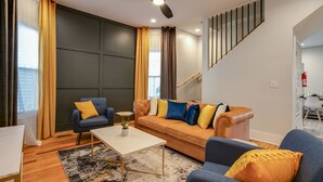 Una sala de estar moderna con un sofá, sillones, una mesa de centro y un ventilador de techo.