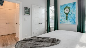 Un dormitorio con una cama, un cuadro de un reloj y una puerta.