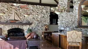Ein rustikales Interieur mit einer Steinwand, einem Kamin und einer Holzbalkendecke.