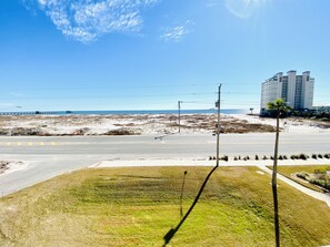 Une route côtière, un ciel dégagé, une plage et, au loin, un immeuble de grande hauteur.