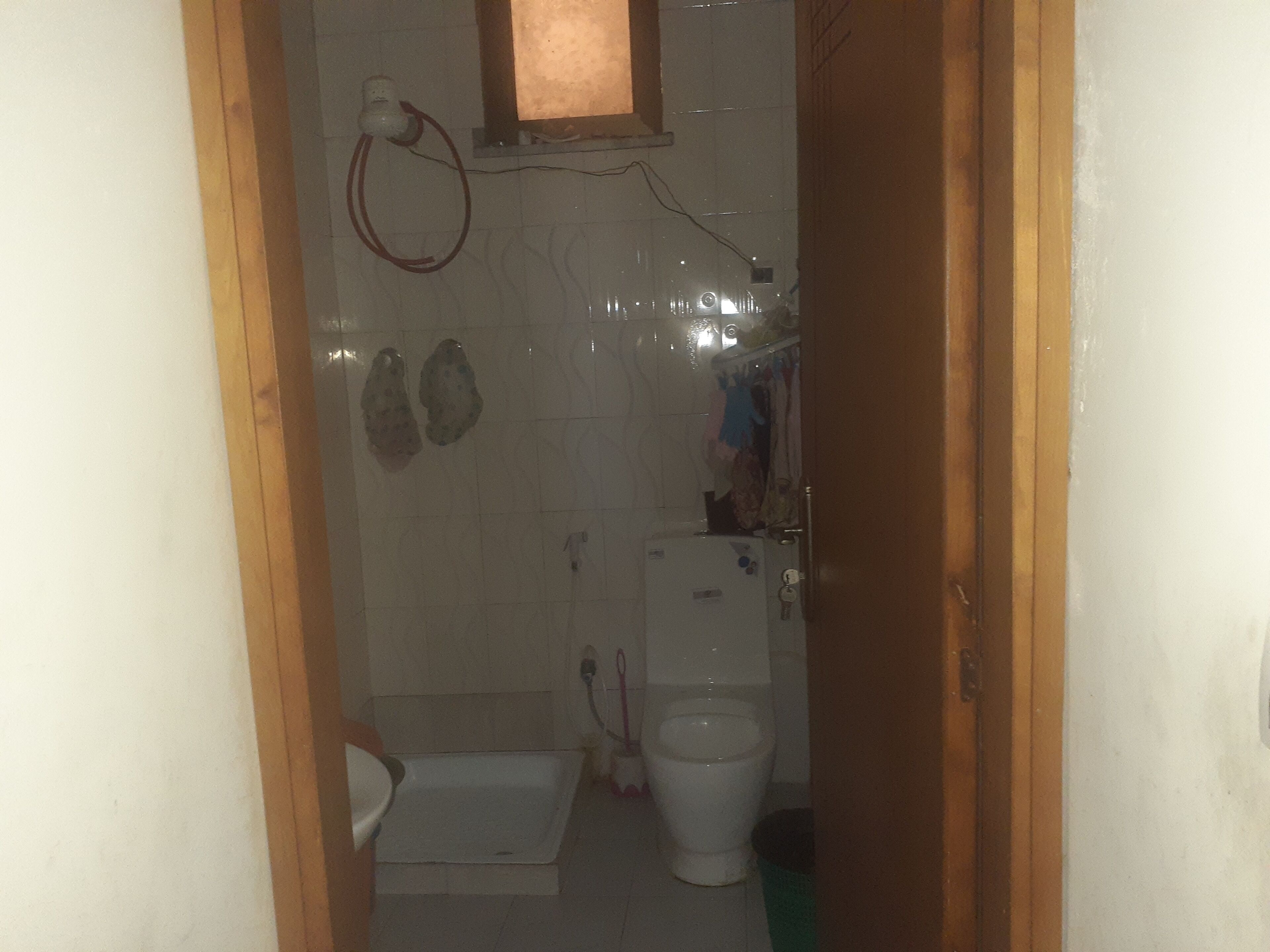 A small bathroom with a toilet, a sink, and a shower area.
