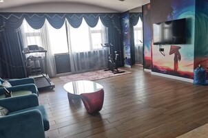 Una habitación con una cinta de correr, una bicicleta estática y una televisión grande en la pared.