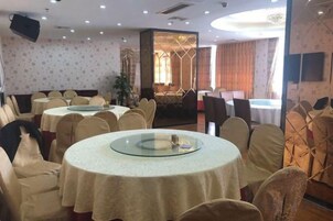 Un área de comedor con mesas redondas, sillas y un separador de vidrio.