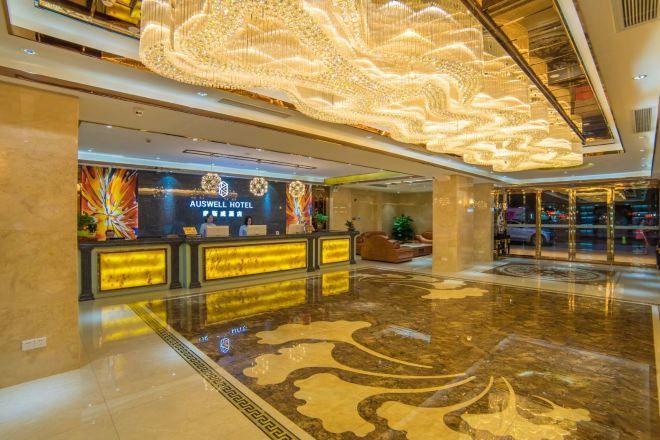 A hotel lobby with a reception desk, a chandelier, and a modern design.