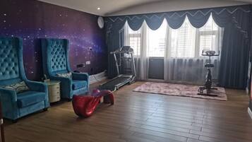 A room with a treadmill, a large blue chair, a red bean bag, and a starry wall mural.