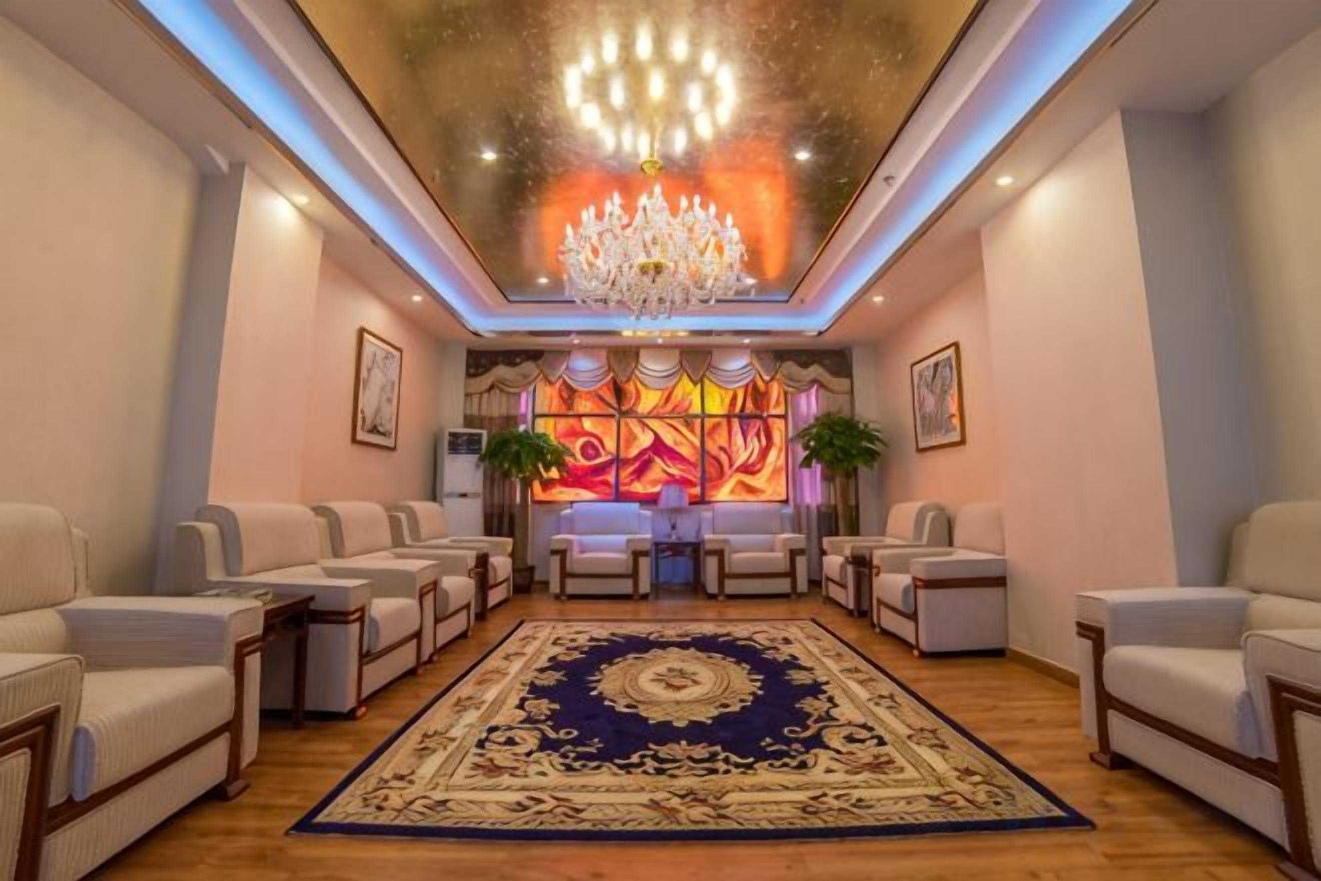 A hotel lobby with a chandelier, sofas, a patterned rug, and artwork on the walls.