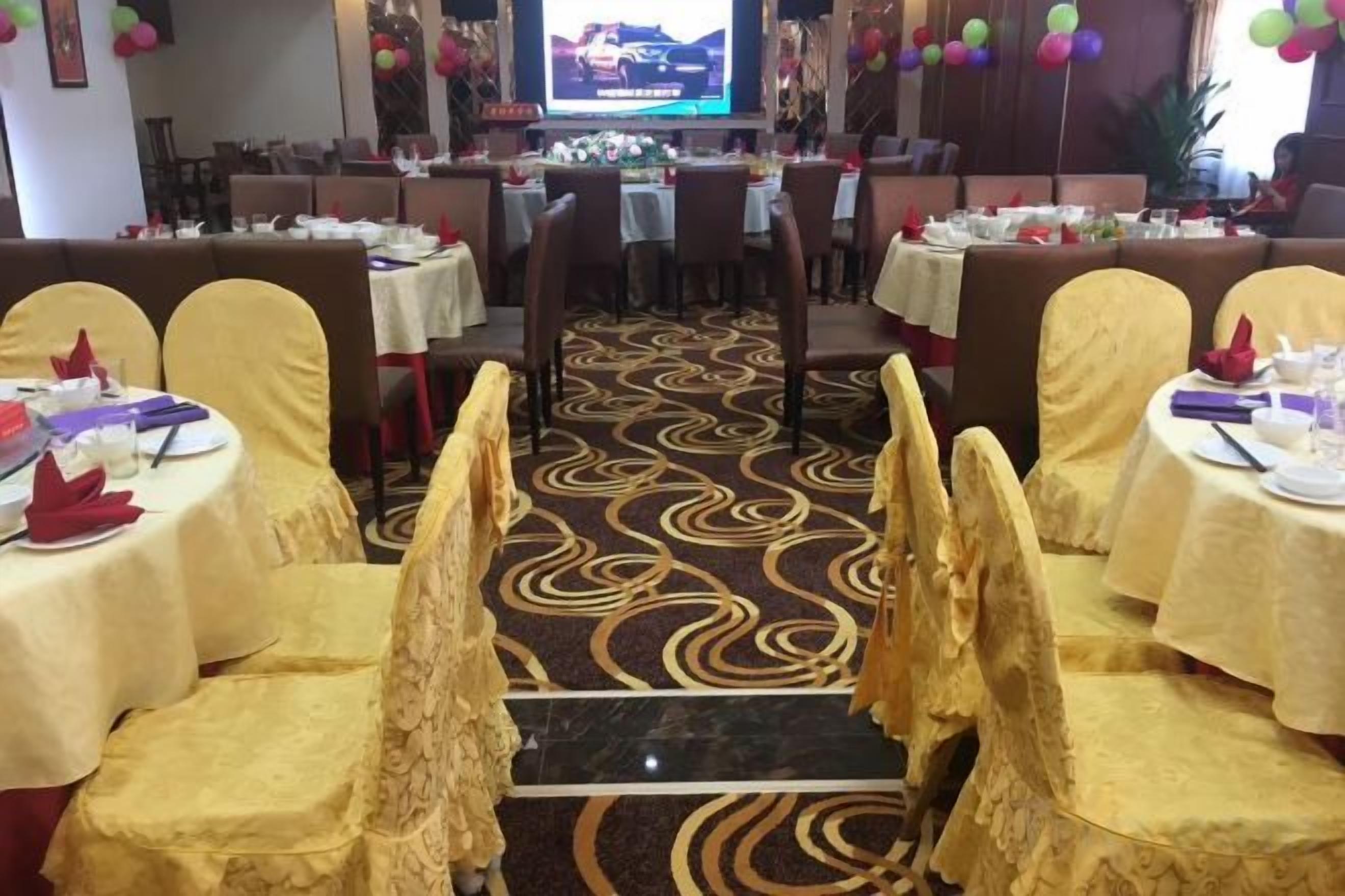 A banquet hall with round tables, chairs, and a carpeted floor.