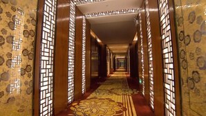 A corridor with patterned walls and a floral carpet. - Rodin Oswey Hotel (Luoding)