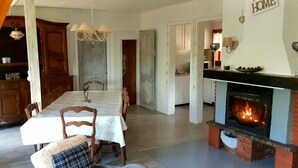 Uma sala de jantar com uma mesa comprida, cadeiras e uma lareira.