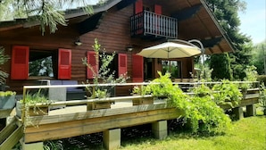 Uma cabana de madeira com varanda, área de estar externa e um deck de madeira.