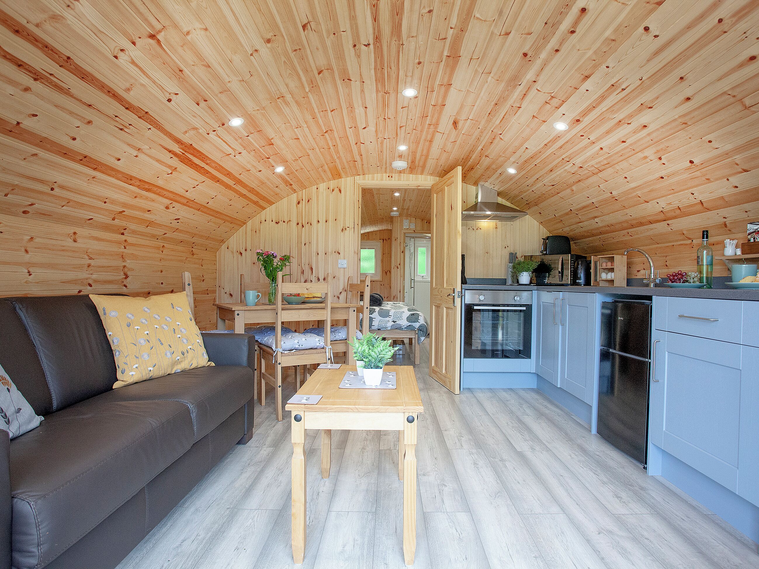 A wooden interior with a sofa, dining table, and kitchen area.