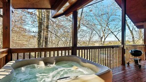 Ein Whirlpool auf einer Holzterrasse mit Blick auf Bäume.