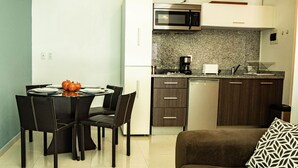 A compact kitchen with a microwave, coffee maker, and a dishwasher. There is a dining table with chairs and a brown sofa with a patterned pillow. - Tiny Apartment with Rooftop pool y GYM (Mexico City)