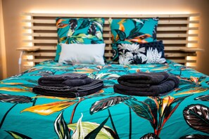 Restful retreat with a vibrant bedspread, two pillows, and a stack of towels at the foot of the bed.