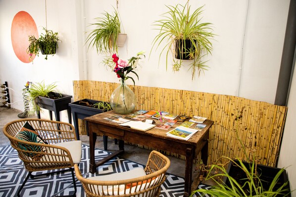Relax in this charming room with a wooden dining table, wicker chairs, and lush greenery.