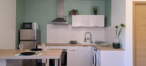 Compact kitchen with modern appliances and minimalist design, featuring a refrigerator, oven, microwave, and washing machine.