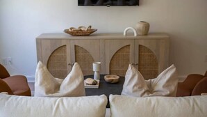A living room with a sofa, a wooden cabinet with two doors, and a television on the wall. - The Ressman Haus at MarktPlatz, Walk to Main St! (Fredericksburg)