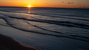 Un coucher de soleil sur l’océan, avec des vagues qui se rapprochent du rivage.