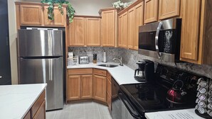Une cuisine moderne avec des meubles en bois, des appareils électroménagers en acier inoxydable et un dosseret carrelé.