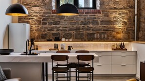A modern kitchen with a stone wall, a white island with bar stools, and a large LG refrigerator.