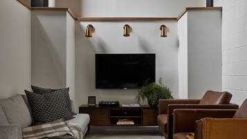 Un salon moderne avec un téléviseur à écran plat, une console en bois, des canapés en cuir et un tapis à motifs.