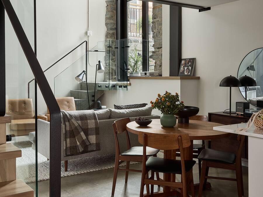 A modern living space with a dining area, a staircase, and a view of the outdoors.