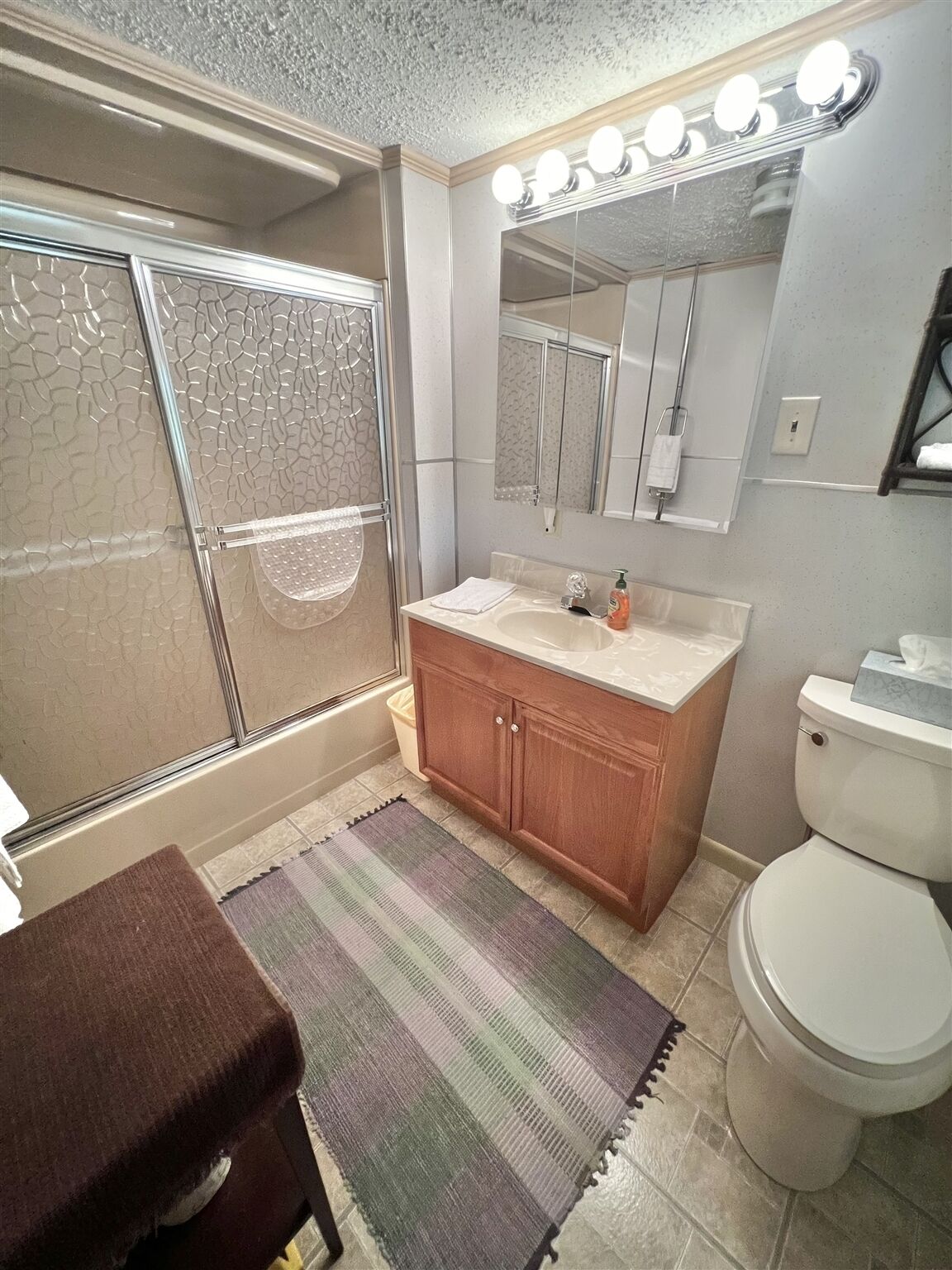 A bathroom with a glass shower enclosure, a vanity with a mirror, and a toilet.