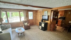 A cozy living room with a sofa, armchair, and coffee table. There is a television and a kitchen area with cabinets and a microwave. - Great Place for a Family Retreat! Sleeps 10 (Naples)