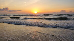 Una playa con olas y un atardecer.