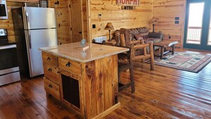 A cozy cabin interior with a wooden interior, a kitchen with a stainless steel refrigerator, a wooden dining table, and a sofa. - Mountain View Cabin,15 Min to Casino, Family Friendly (murphy)