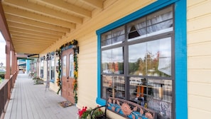 A wooden building with a porch, large windows, and a door with a wreath.