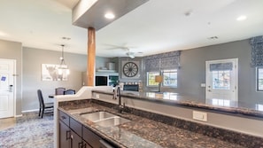 A modern kitchen with granite countertops, a central island, and a built-in oven.