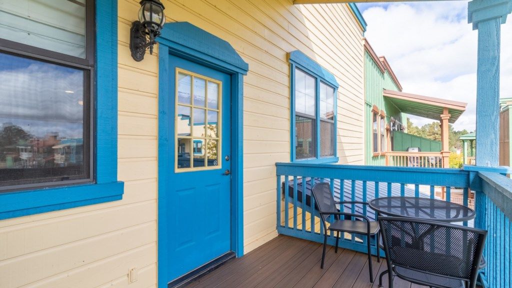 A blue door, a window, and a balcony with a table and chairs.