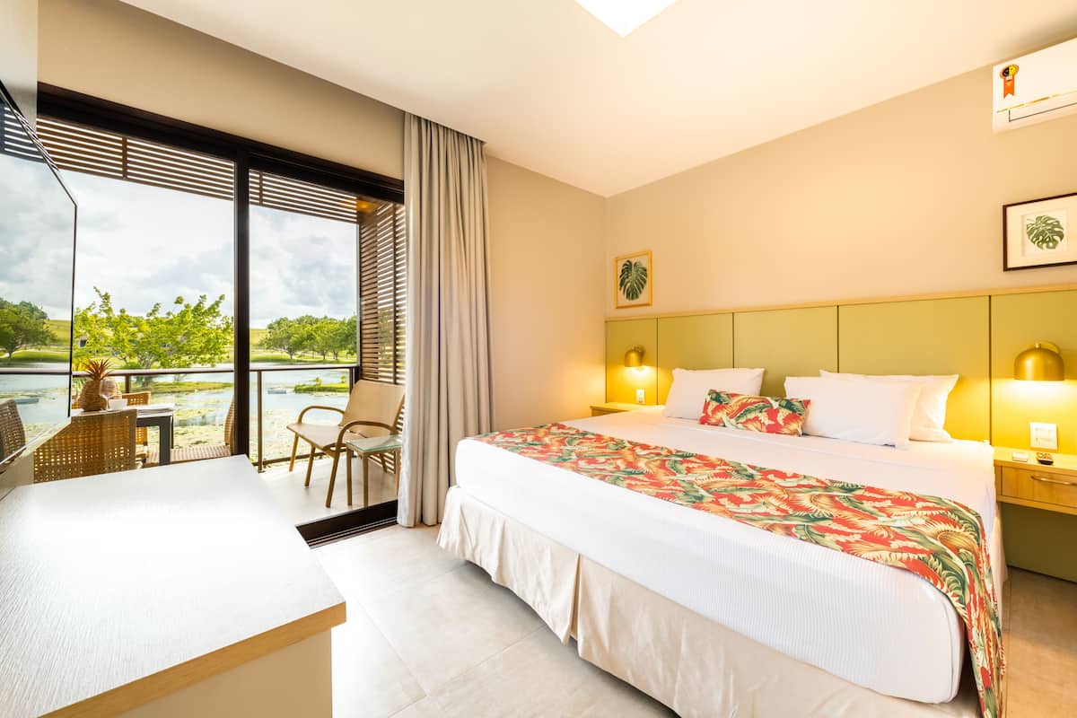 Una habitación de hotel con una cama grande, un escritorio y vistas a un cuerpo de agua.