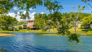 A lakeside view with buildings, trees, and a clear sky. - Reservas dos Lagos - Boa Luz (Laranjeiras)