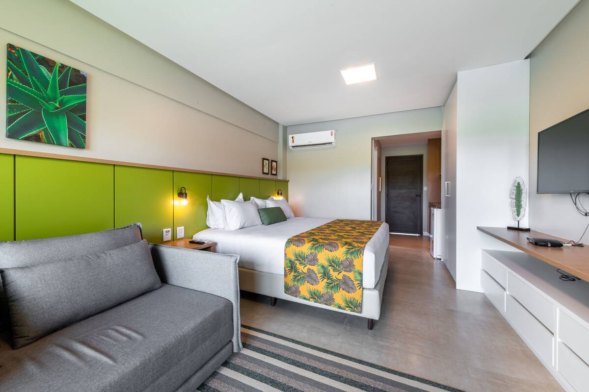 Una habitación de hotel moderna con una cama, un sofá, un escritorio y una televisión.