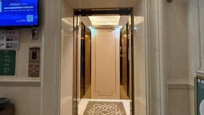 An elevator interior with a modern design, a digital display, and a patterned floor.